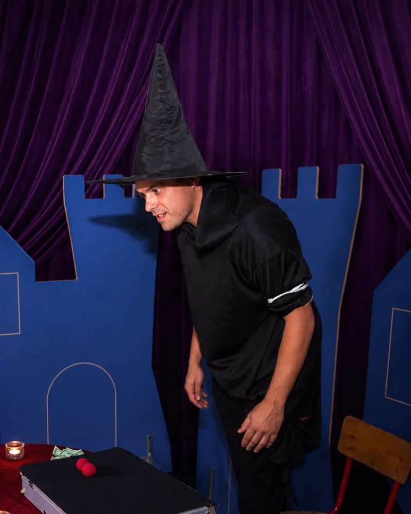 Magicien pour enfants sur scène avec un chapeau de sorcier et des accessoires de magie