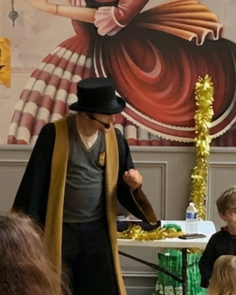 Magicien pour enfants sur scène avec un haut-de-forme pendant son spectacle interactif
