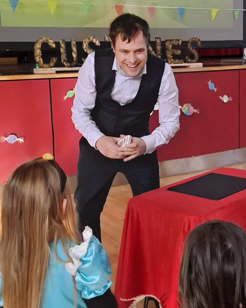 Magicien pour enfants réalisant un tour de cartes à son jeune public